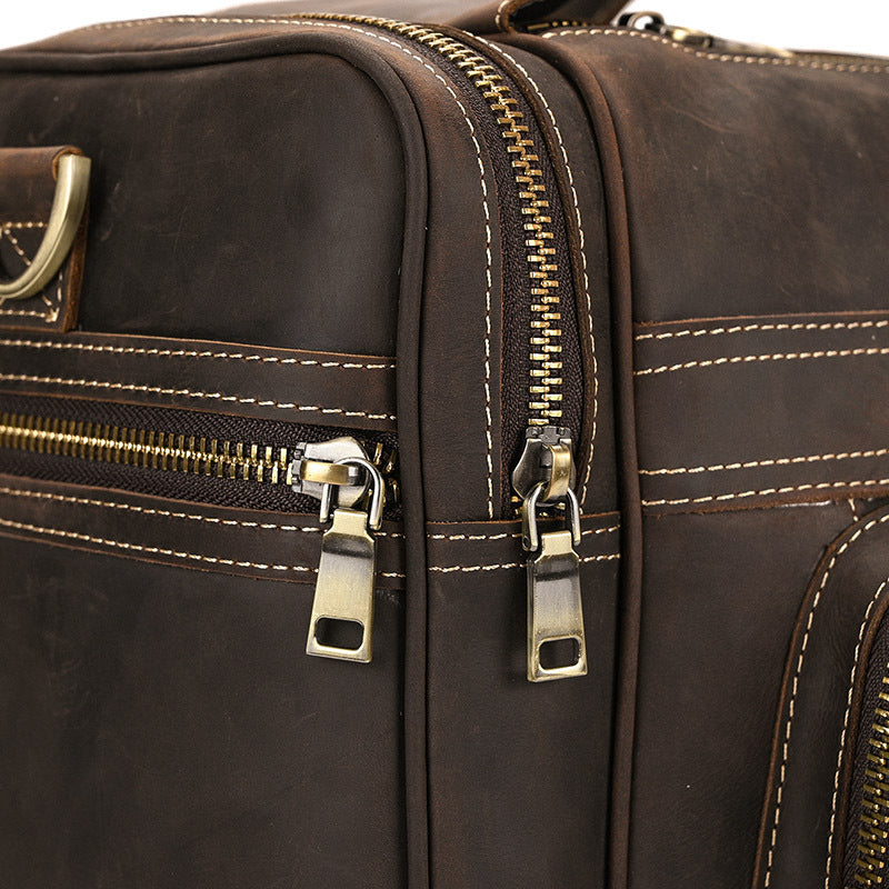 Close-up of a brown leather bag with gold zipper and stitching details.