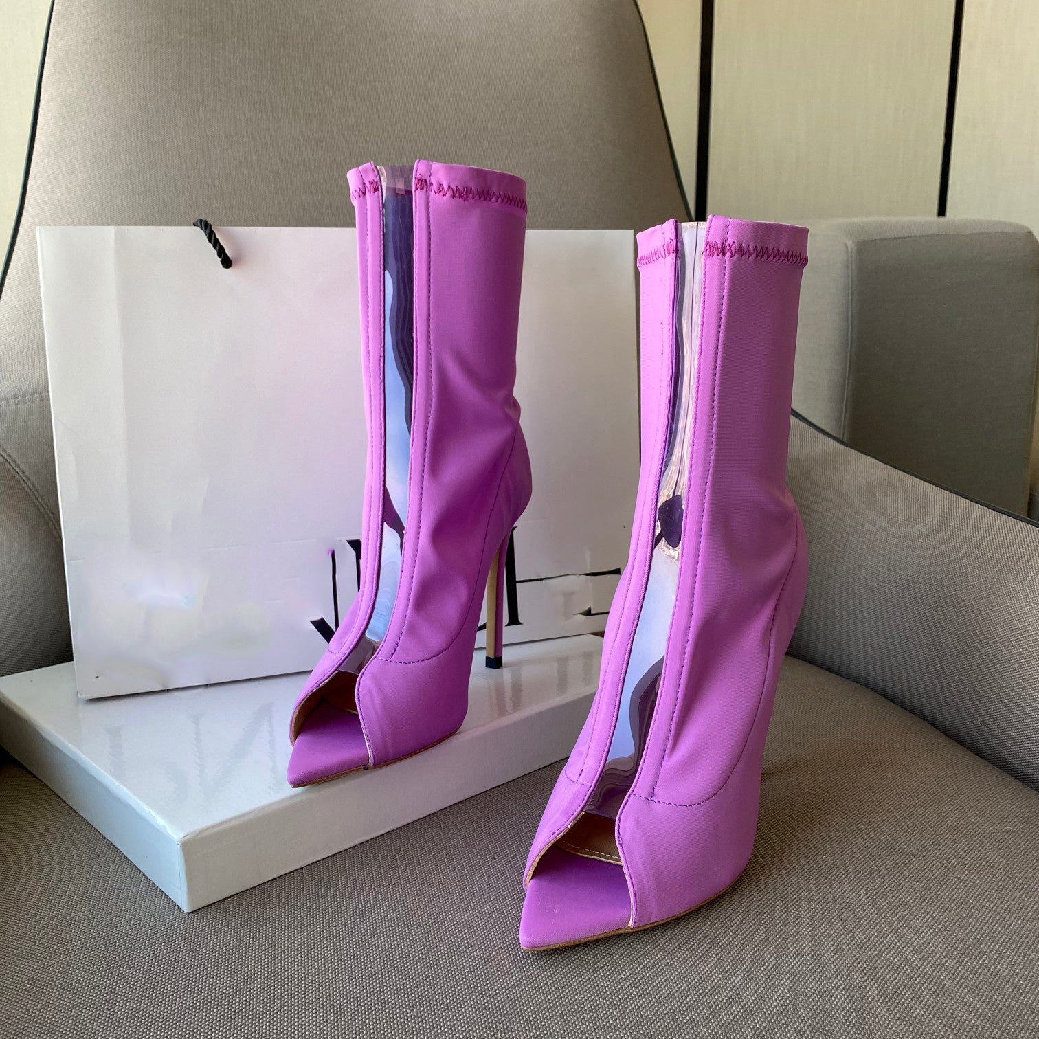 Purple high-heeled boots on a gray surface with a white box in the background