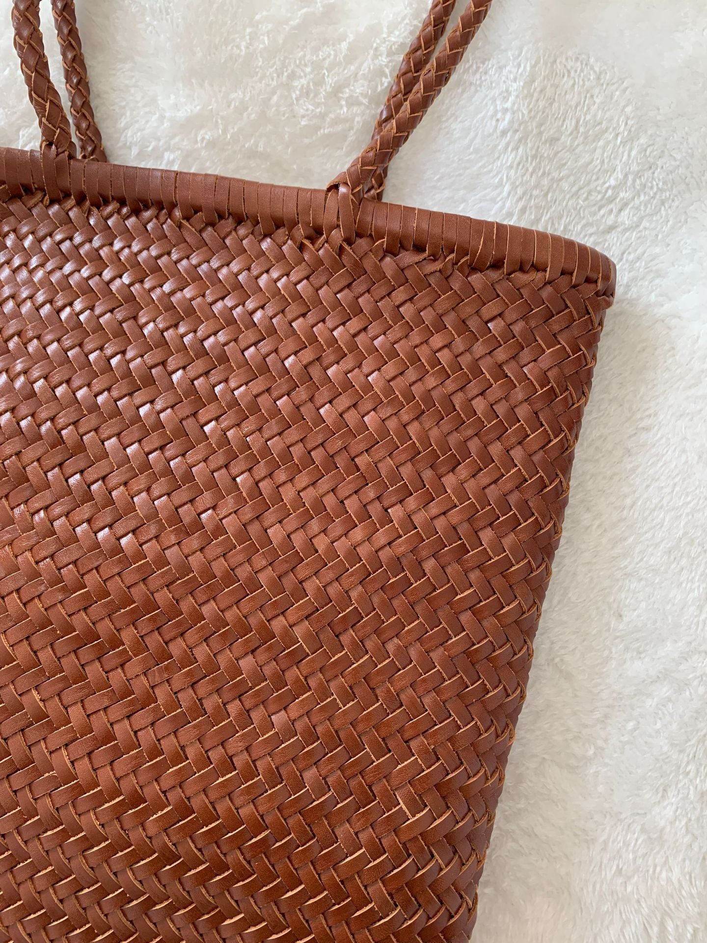 Brown woven bag on a textured white background