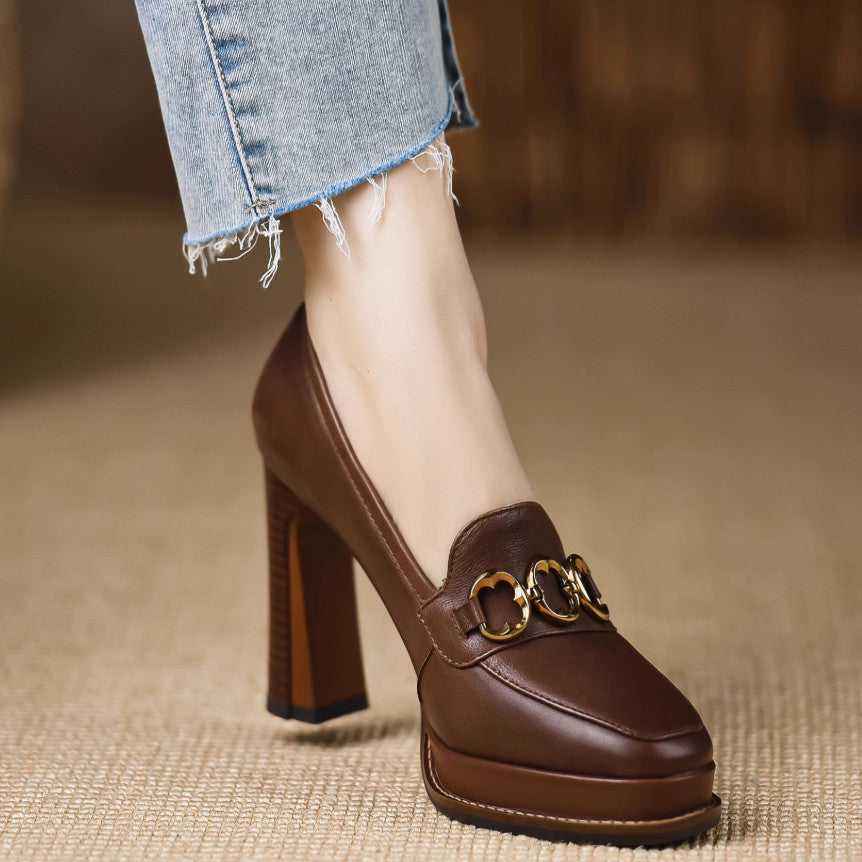 Brown leather shoe with gold buckle on a blurred background