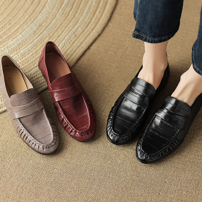 Three pairs of loafers in different colors on a textured surface.