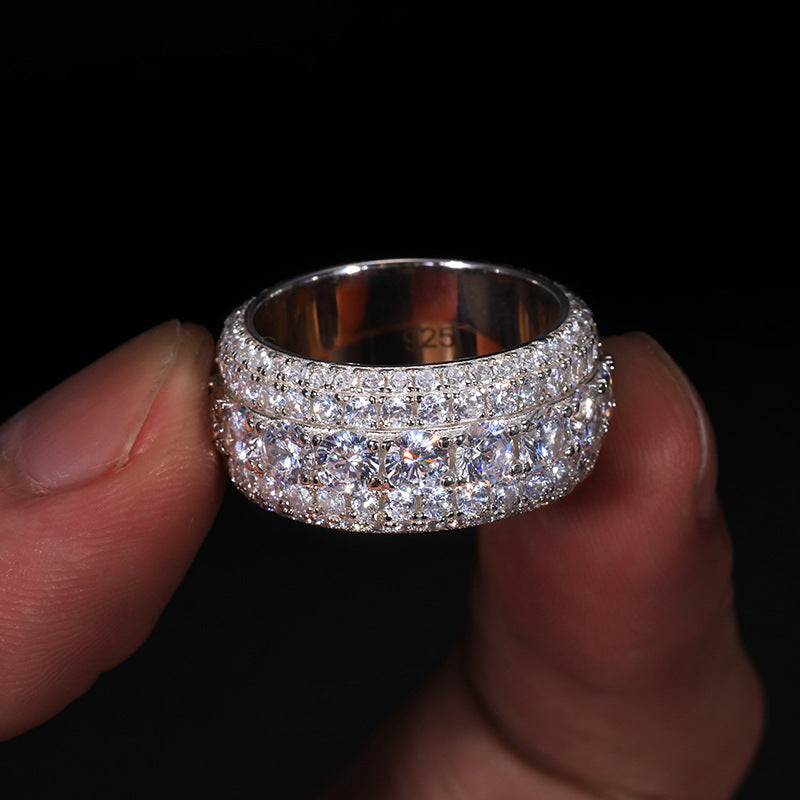 Silver ring with multiple diamond settings held between fingers against a black background