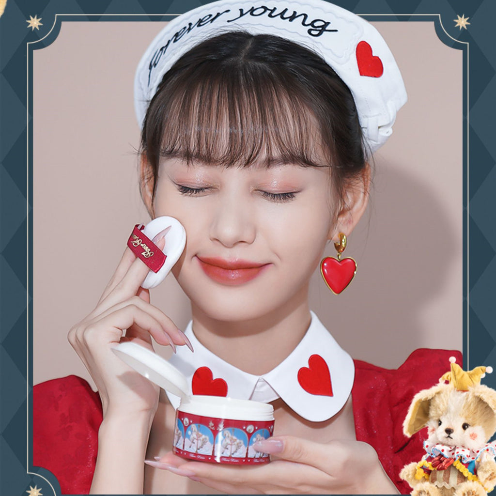 Woman wearing a headband with heart shapes, holding a cosmetic product, and a teddy bear in the corner.