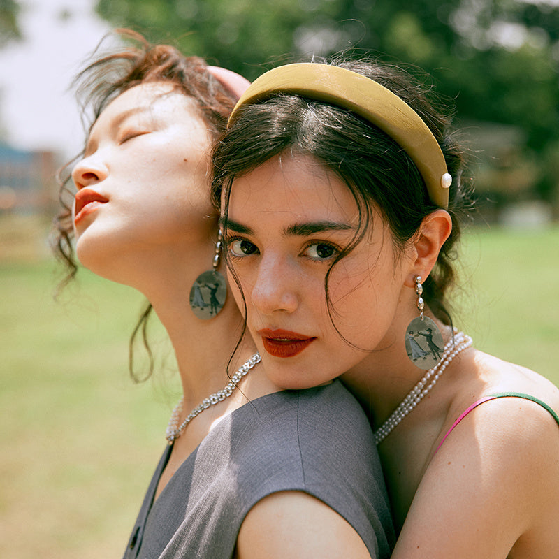Two women standing close together with a blurred natural background