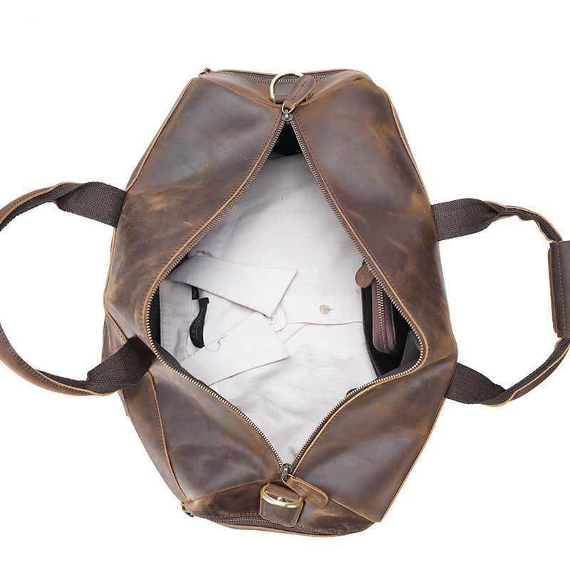 Brown leather duffel bag with white interior on a white background