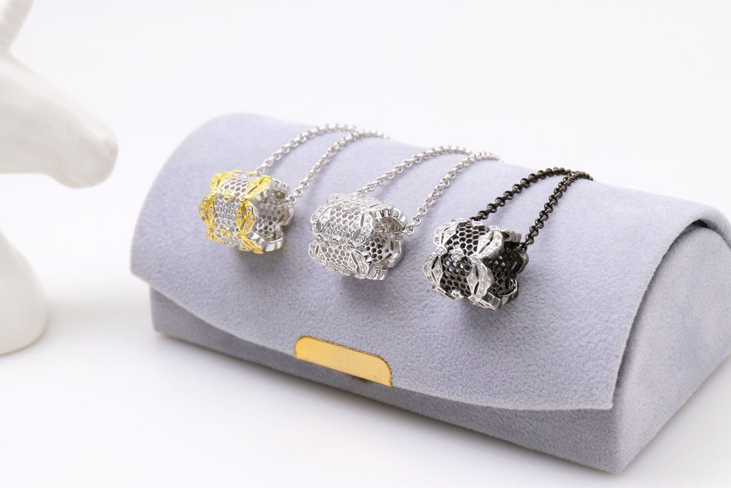 Three necklaces with different pendants on a gray jewelry box.