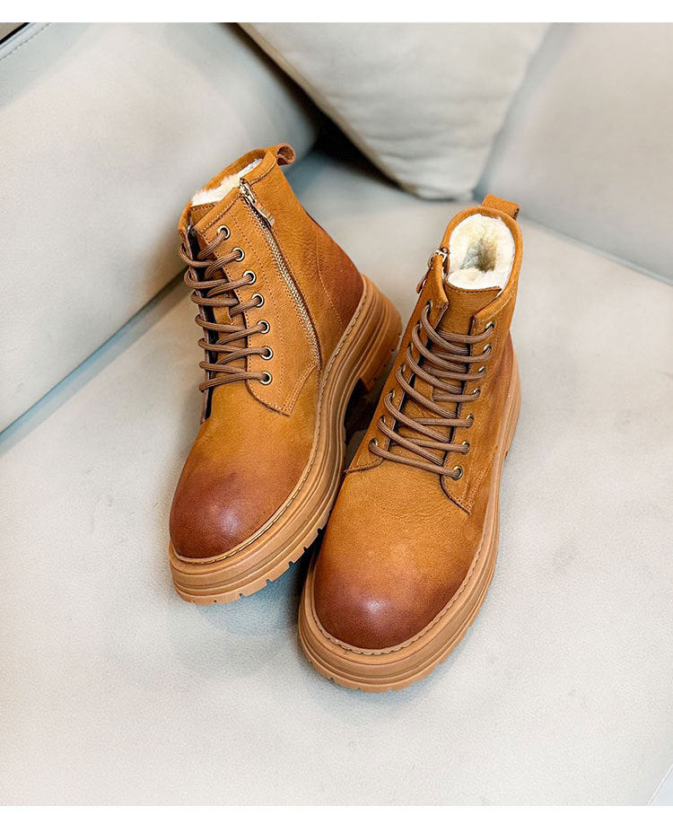 Pair of brown leather boots with fur lining on a light gray surface.