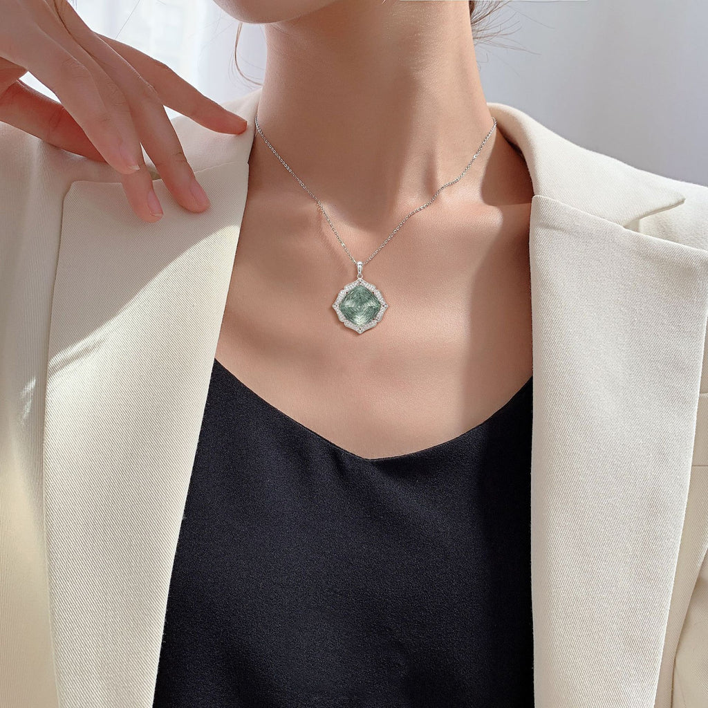 Person wearing a necklace with a green pendant against a neutral background