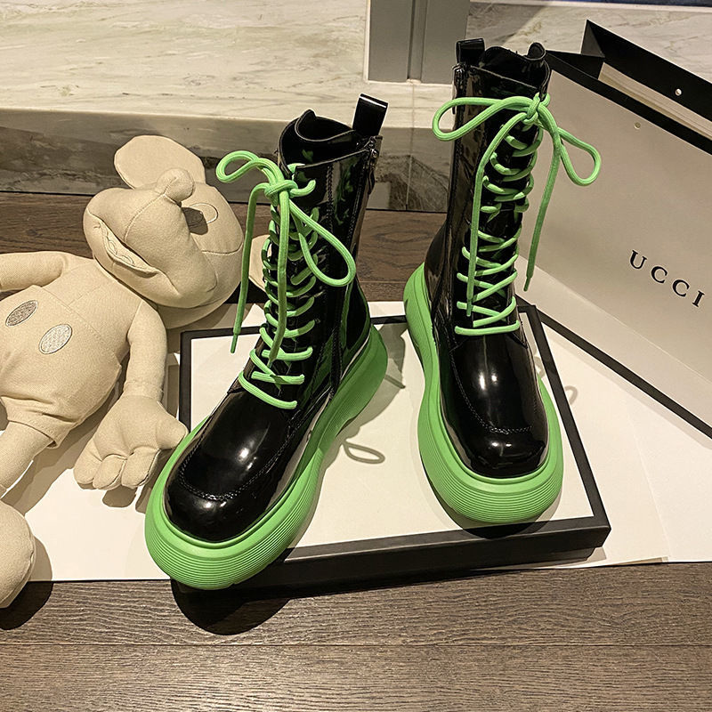 Black and green boots with a plush toy and Gucci box in the background