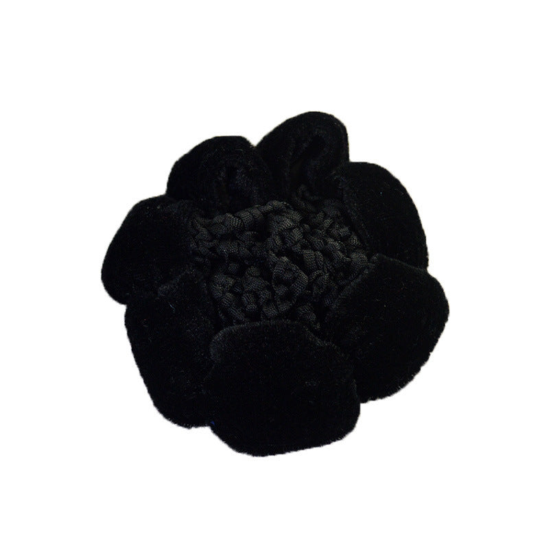 Black flower-shaped hair accessory on a white background