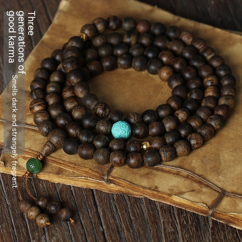 Wooden prayer beads with a turquoise bead on an old book