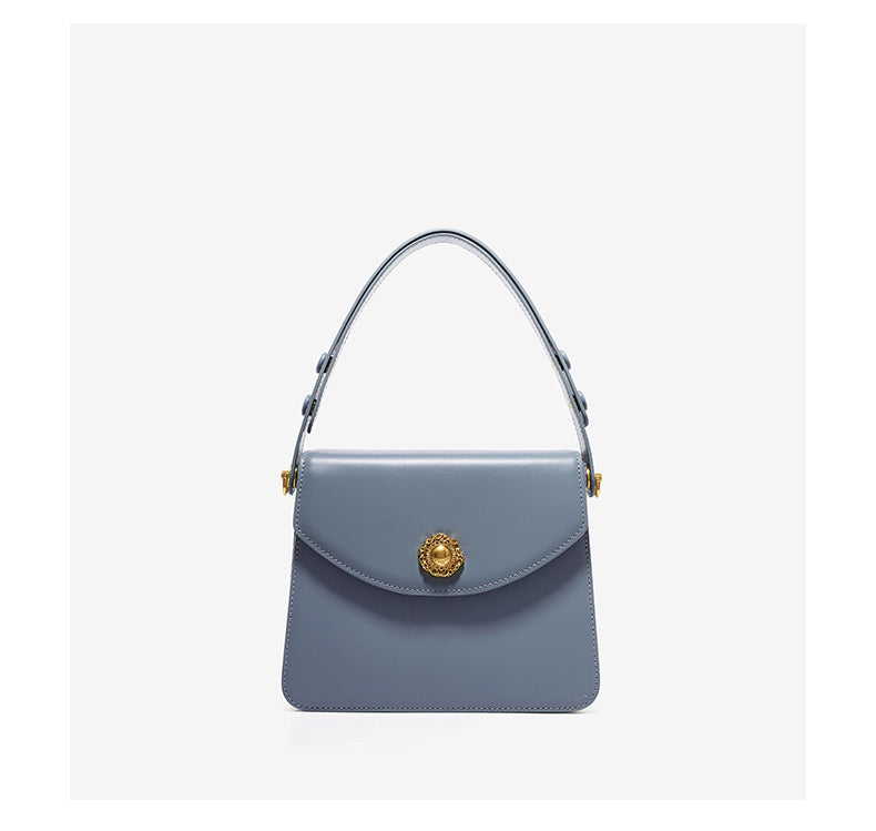 Gray handbag with a gold emblem on a light gray background