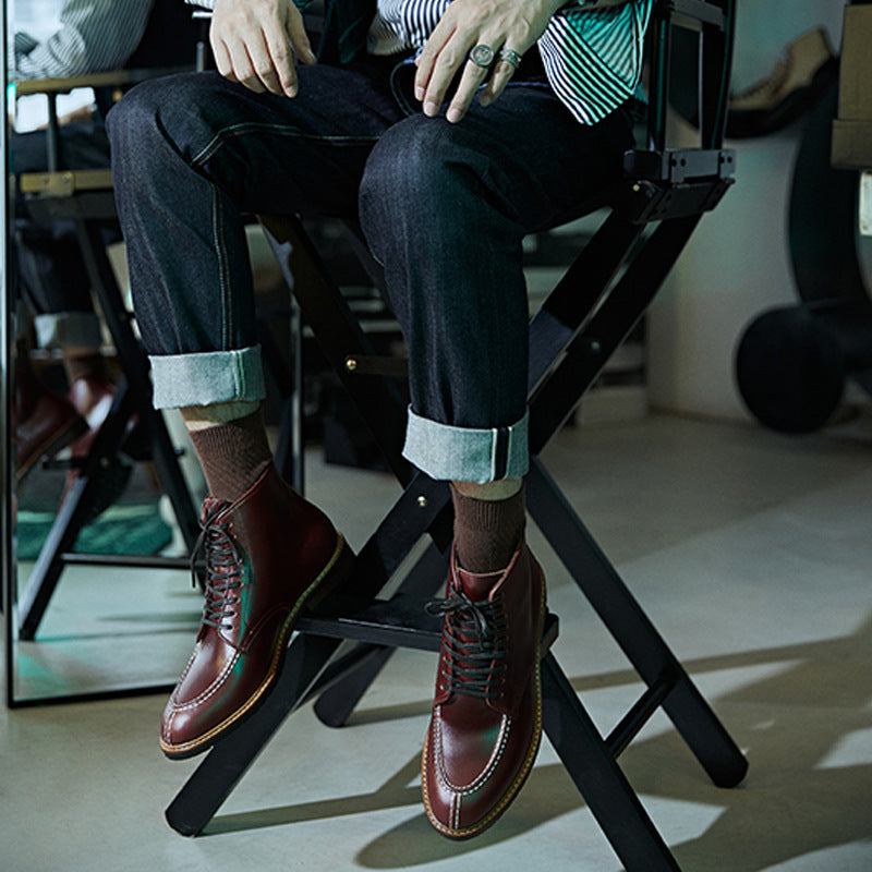 Person wearing brown leather boots sitting on a chair with a blurred background