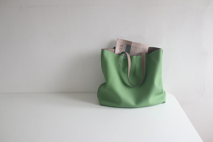 Green tote bag with a brown interior on a white surface