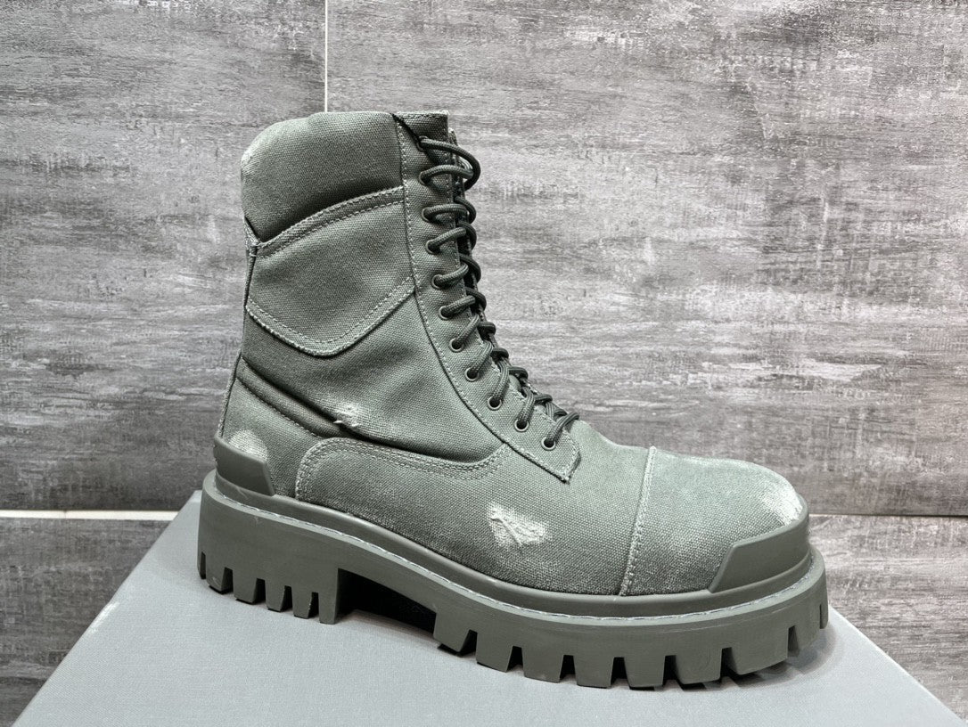 Green high-top boot with thick sole on a gray platform against a tiled wall background