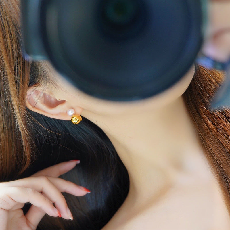 Close-up of a person wearing gold earrings with a blurred background