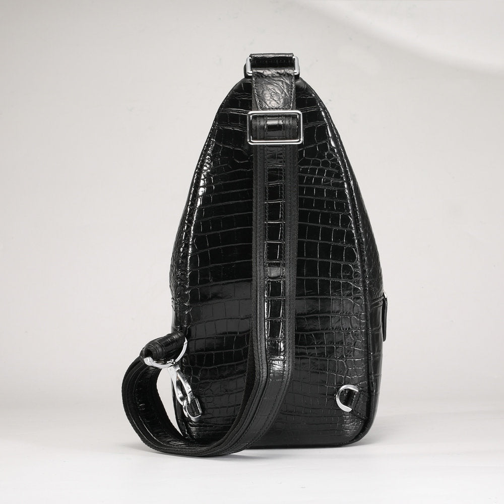 Black crocodile skin sling bag on a white background