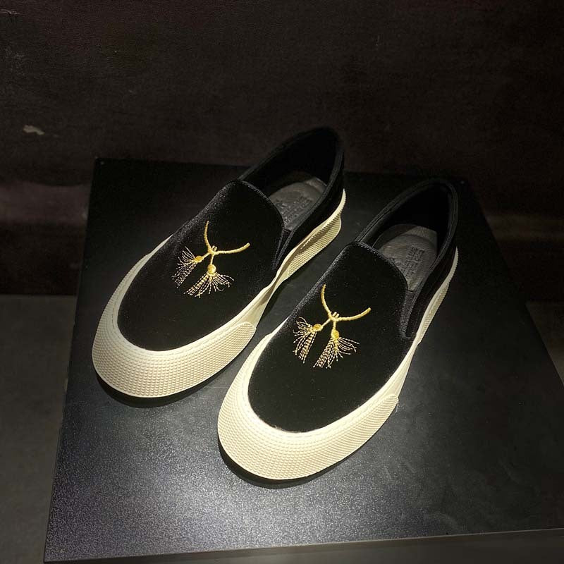Black loafers with gold embroidery on a dark surface