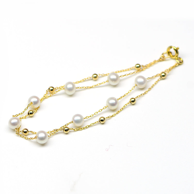 Gold chain necklace with pearls on a white background