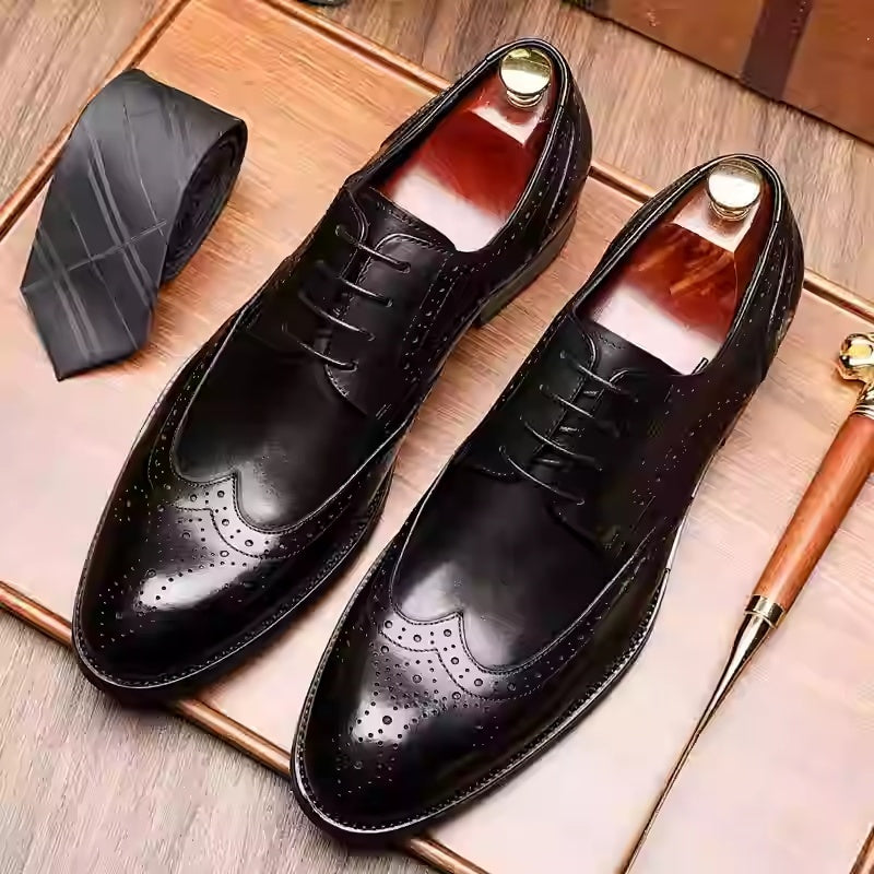 Pair of black dress shoes with a tie and walking cane on a wooden surface