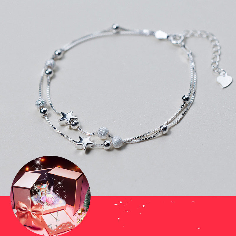 Silver bracelet with star and heart charms on a gray background
