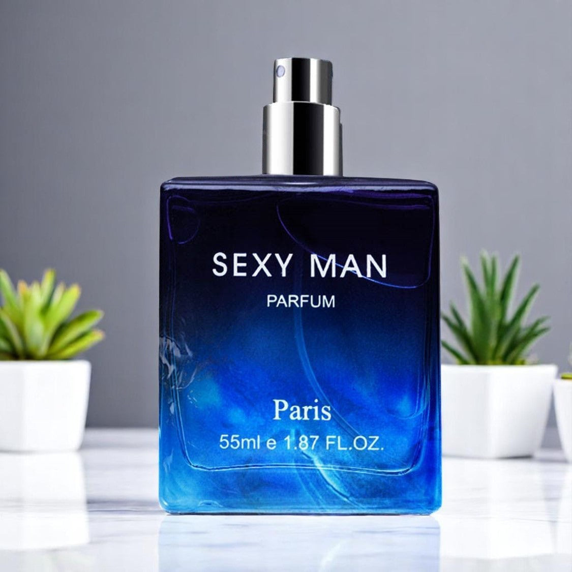 Blue perfume bottle labeled 'Sexy Man Parfum Paris' on a gray background with plants.