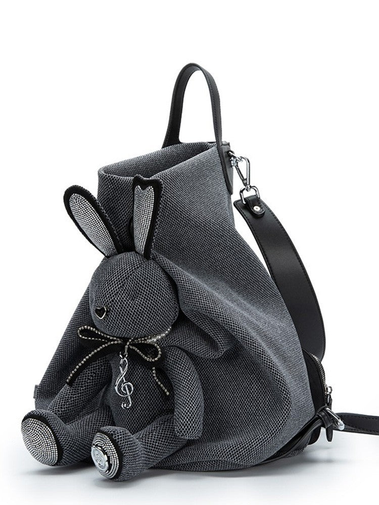 Gray backpack with a plush rabbit toy attached on a white background