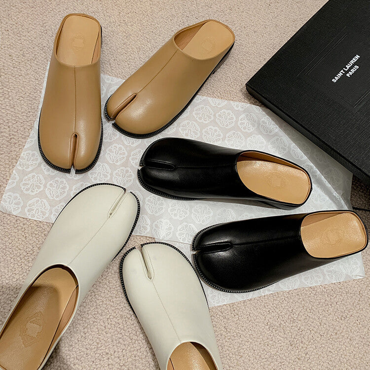 Pair of beige and black shoes on a textured surface with a brand name visible.