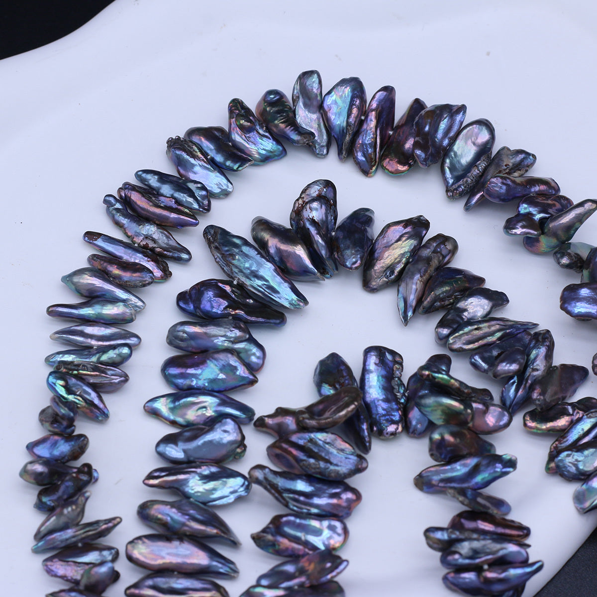 Necklace made of dark, iridescent pearls on a white background