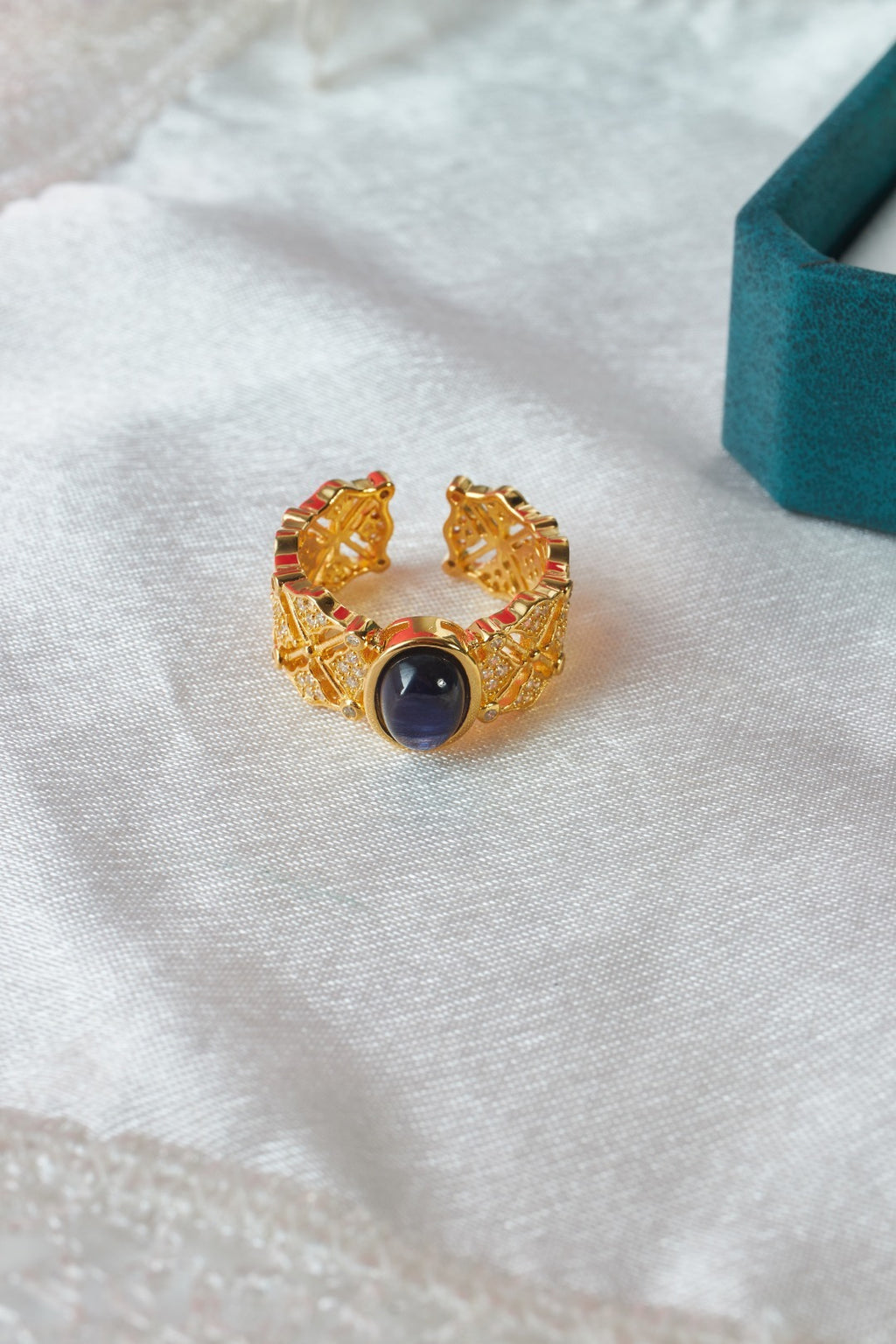 Gold ring with a dark gemstone on a white fabric background