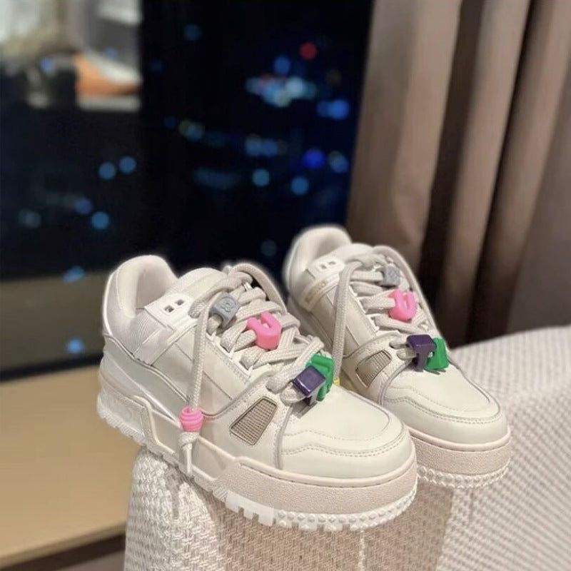Beige sneakers with colorful laces on a textured surface
