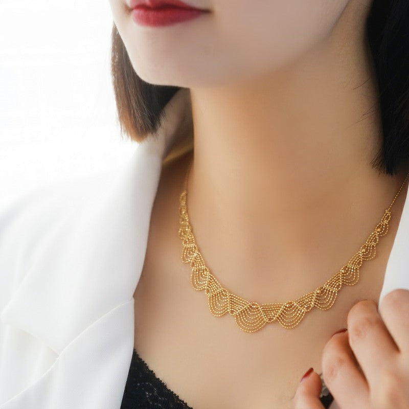 Gold necklace being worn by a person with a white background