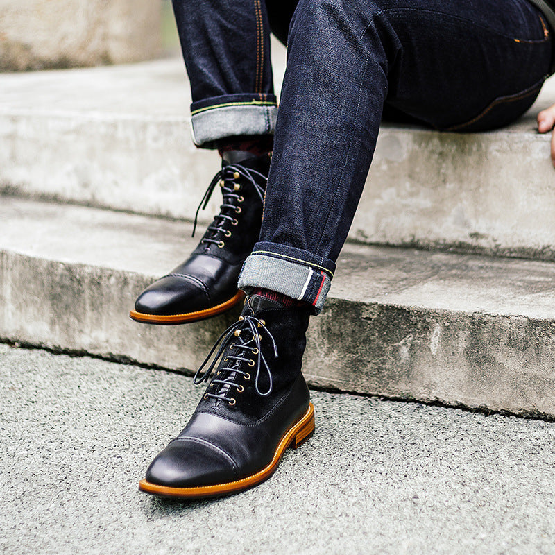 Person wearing black leather boots with orange soles on concrete steps.
