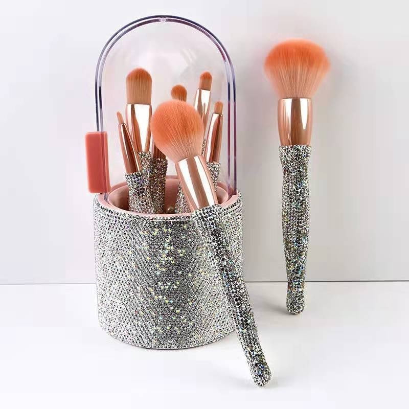 Makeup brushes with glittery handles in a clear holder on a white background
