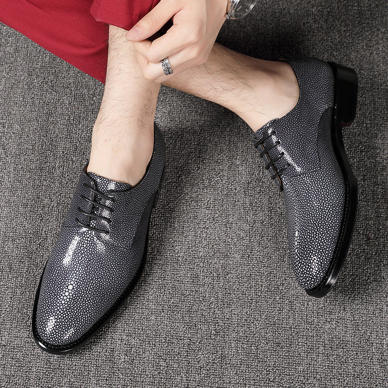 Person wearing black textured dress shoes on a gray carpet