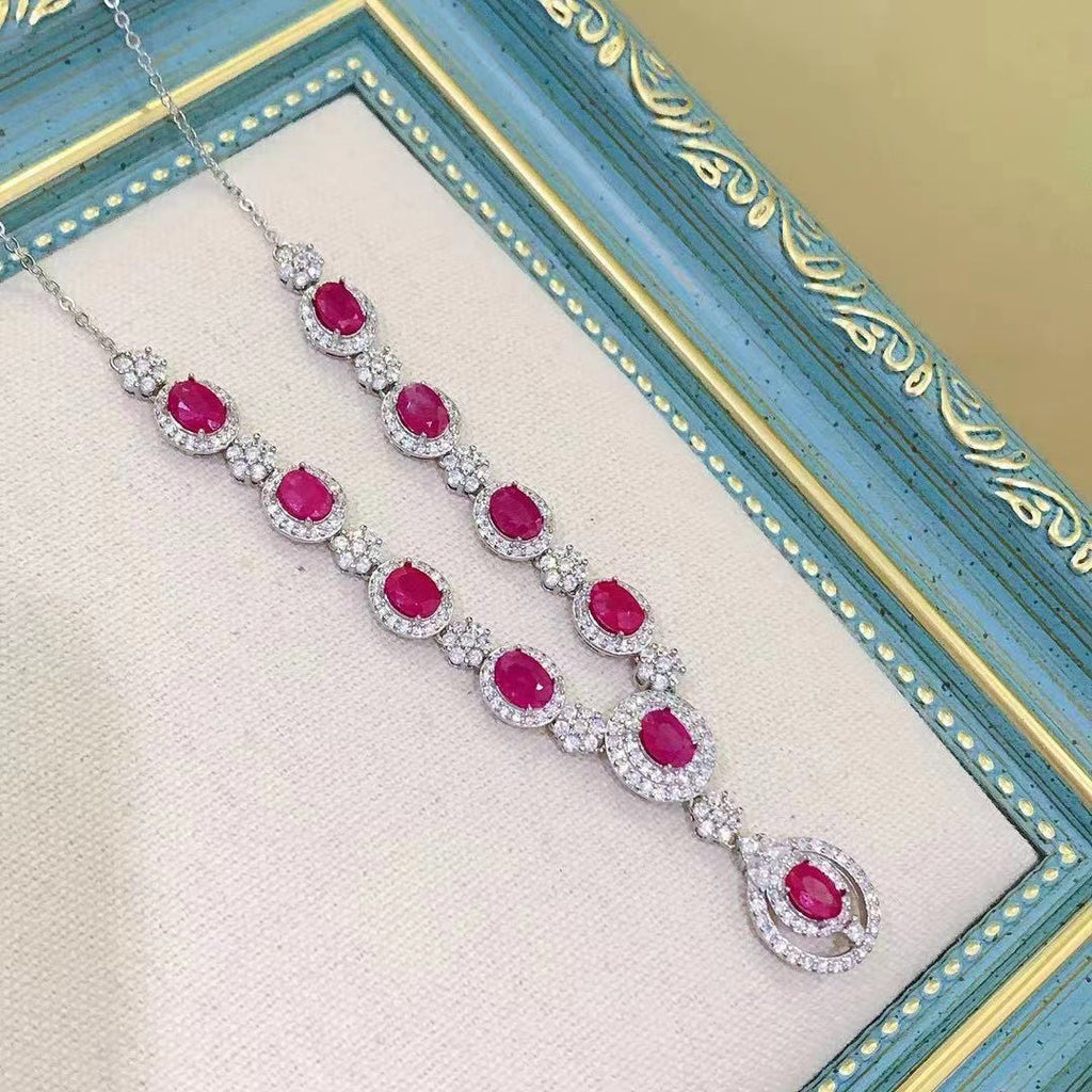 Necklace with red gemstones and diamonds on a decorative blue and gold frame