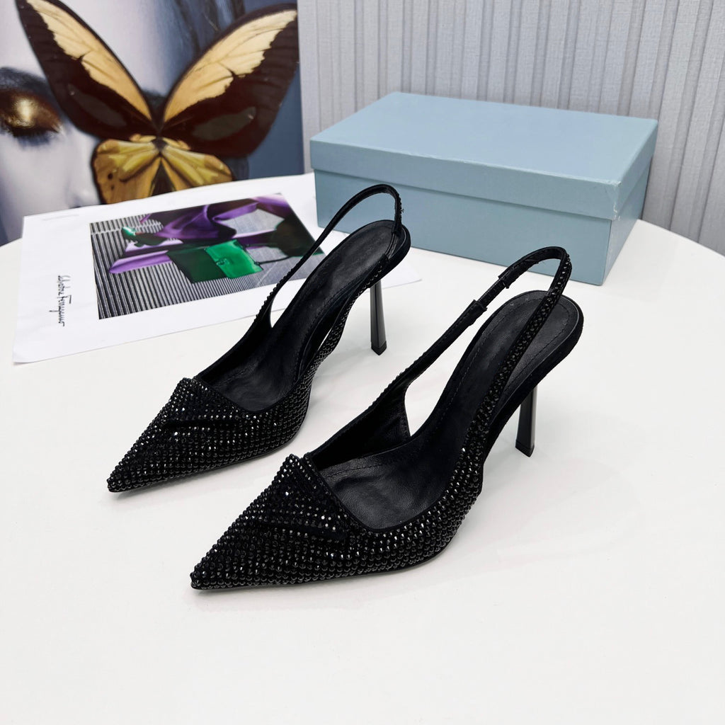 Black stiletto shoes with crystal embellishments on a white surface with a butterfly and magazine in the background.
