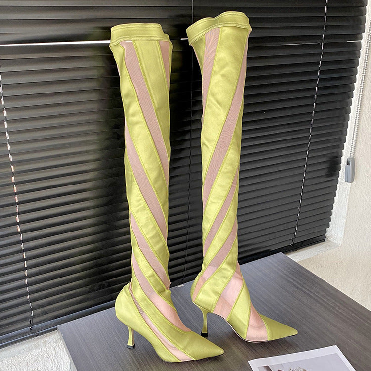 Yellow knee-high boots with pink stripes on a wooden floor.