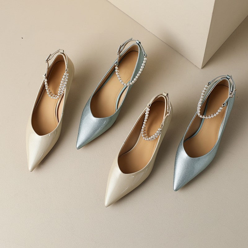 Pair of metallic pointed-toe shoes with embellished straps on a beige background