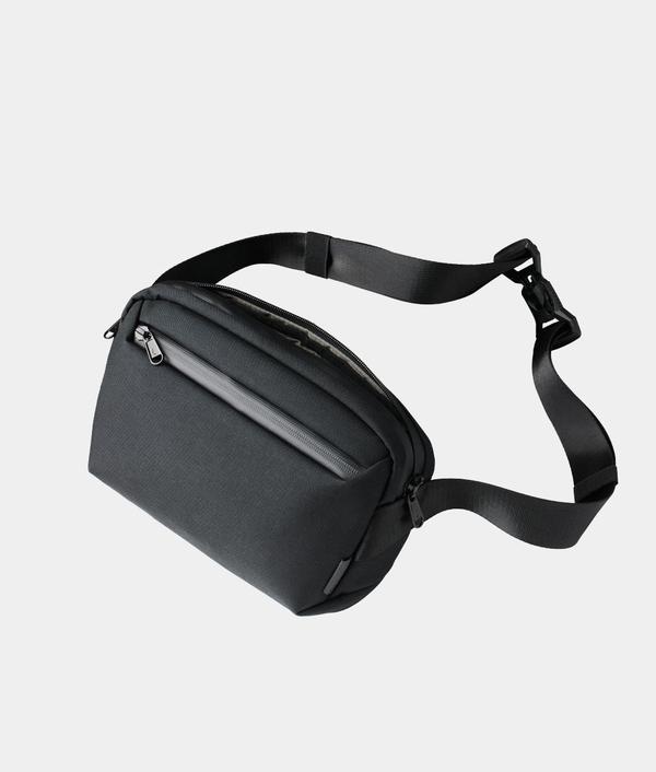 Black waist bag with a strap on a light gray background