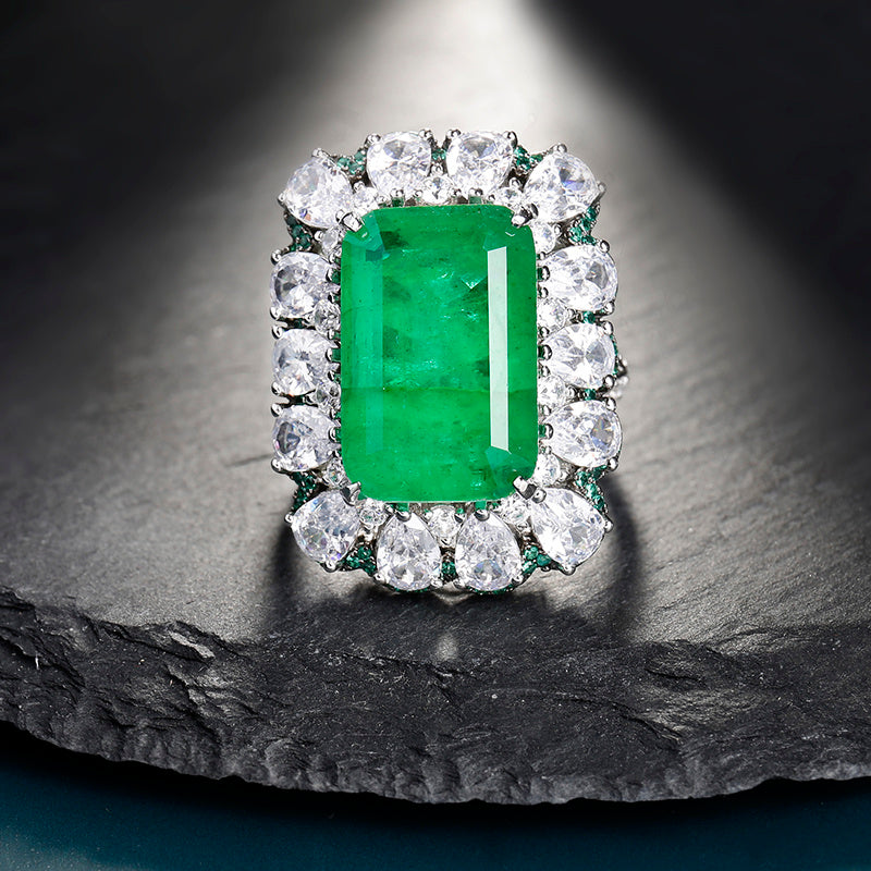 Ring with a green gemstone and diamond accents on a dark stone surface
