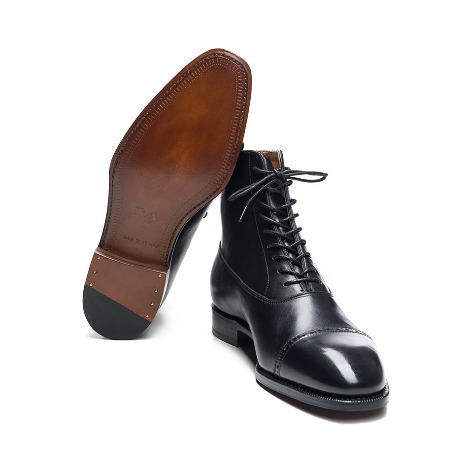 Black leather boot with brown sole on a white background