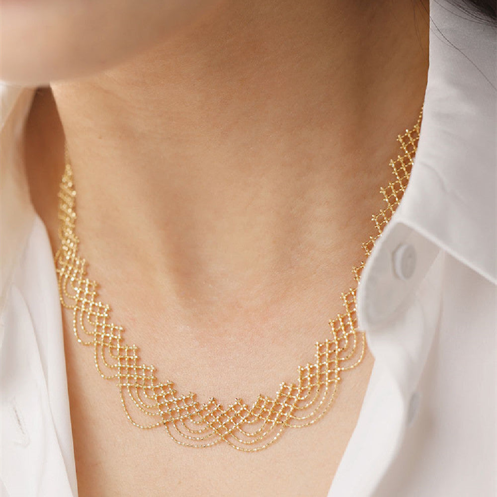 Gold necklace worn by a person with a white shirt