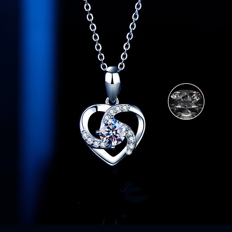 Silver heart-shaped necklace with a central gemstone on a dark background