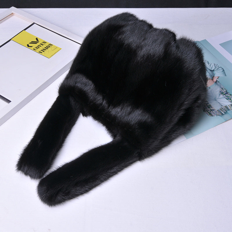 Black fur coat on a white surface with a magazine underneath