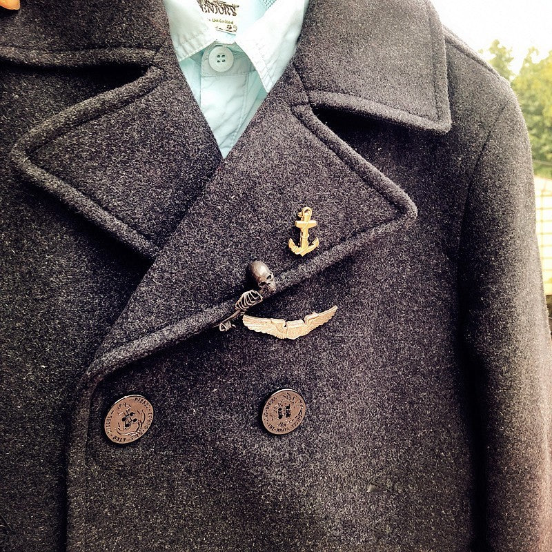 Close-up of a dark coat with buttons and an anchor emblem.