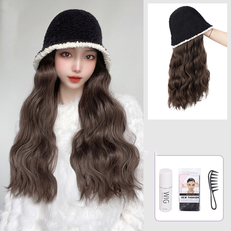 Woman wearing a black hat with a white rim and long wavy brown hair extensions, with additional accessories displayed.