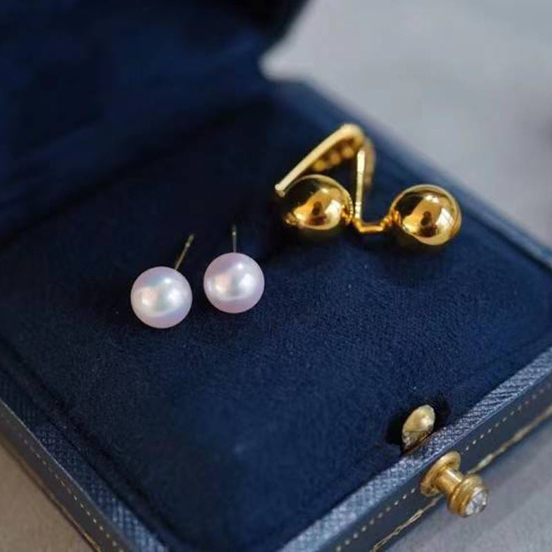 Gold and pearl earrings on a blue jewelry box