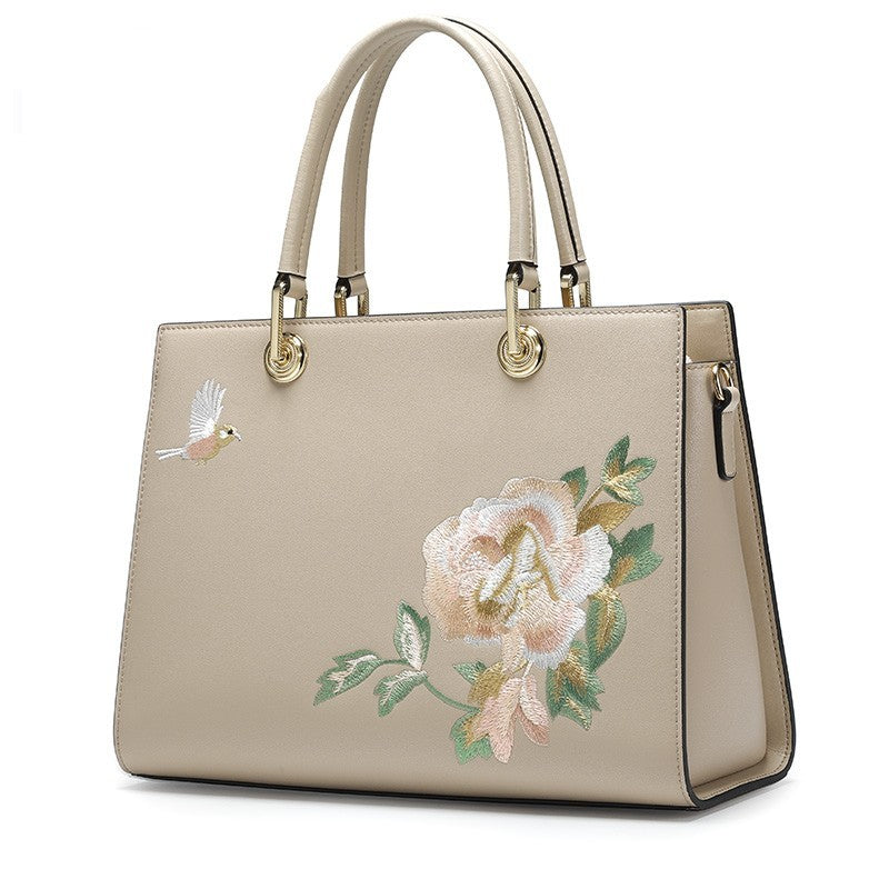Beige handbag with floral embroidery on a white background