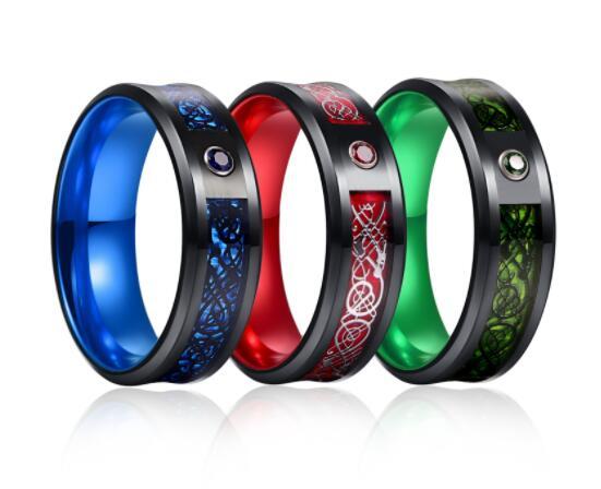 Four metallic rings in blue, red, green, and black with engraved designs on a white background.